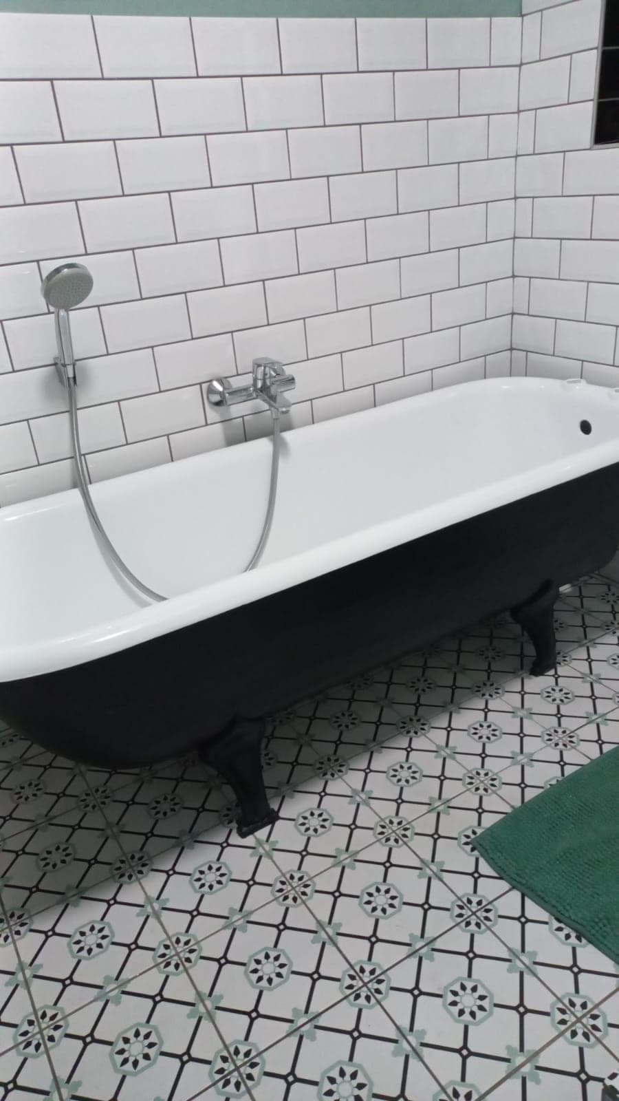 Black clawfoot bath with chrome mixer against white subway tiles