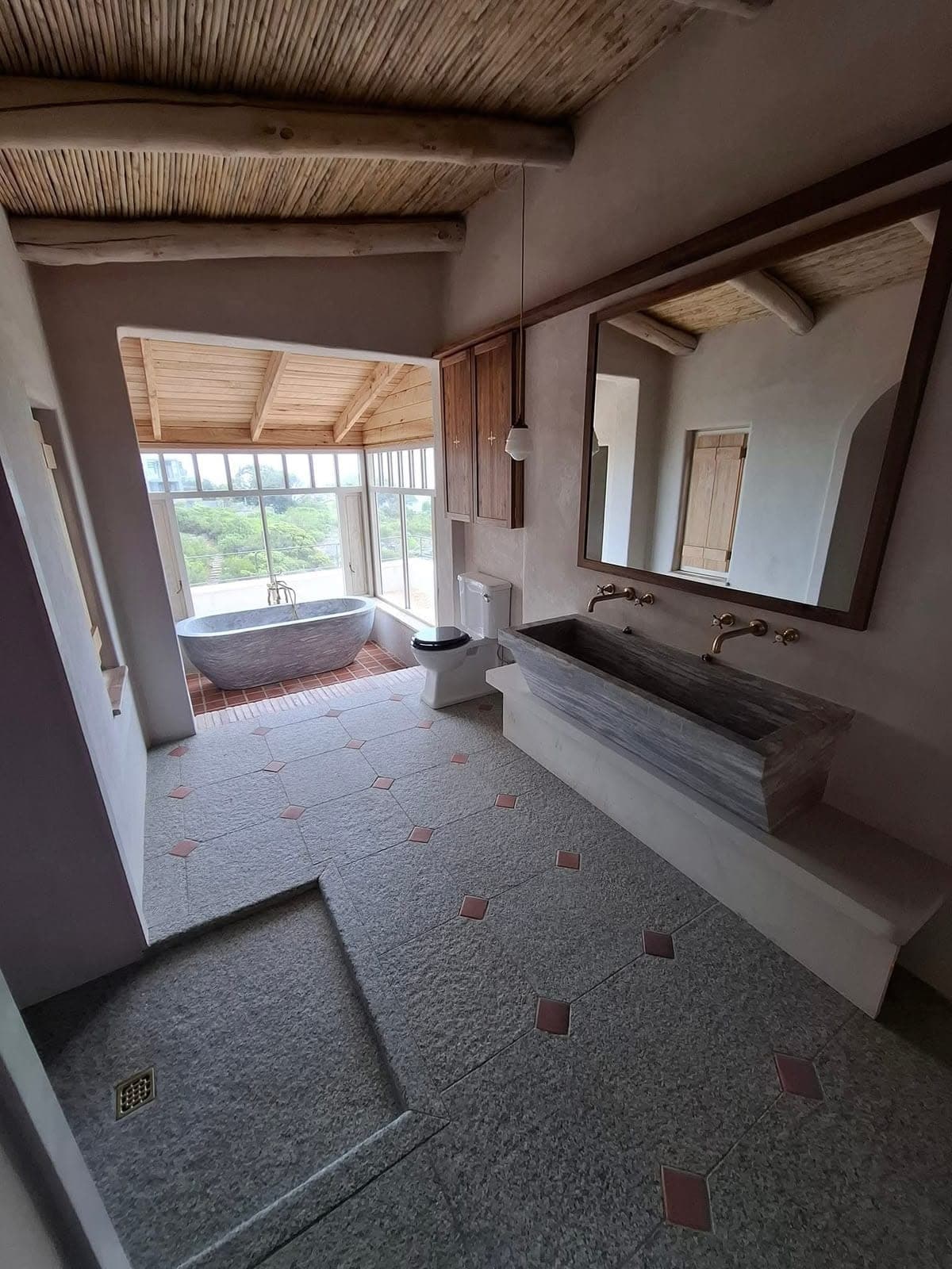 Bathroom fit-out with stone trough basin, brass taps and freestanding stone bath